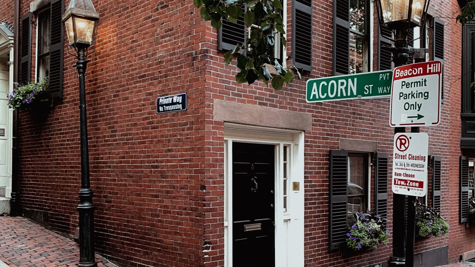 Editorial photograph of an old Boston brick storefront at dusk with warm light glowing through paned windows.