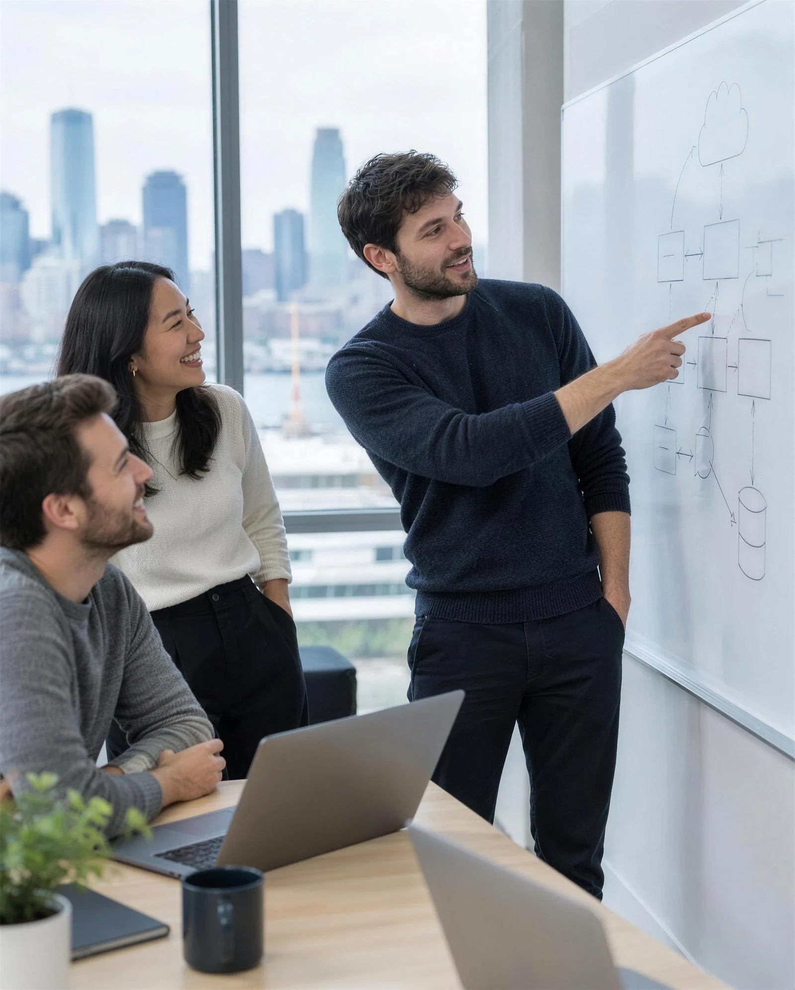 An engineer mapping out an app's architecture on a whiteboard with two teammates